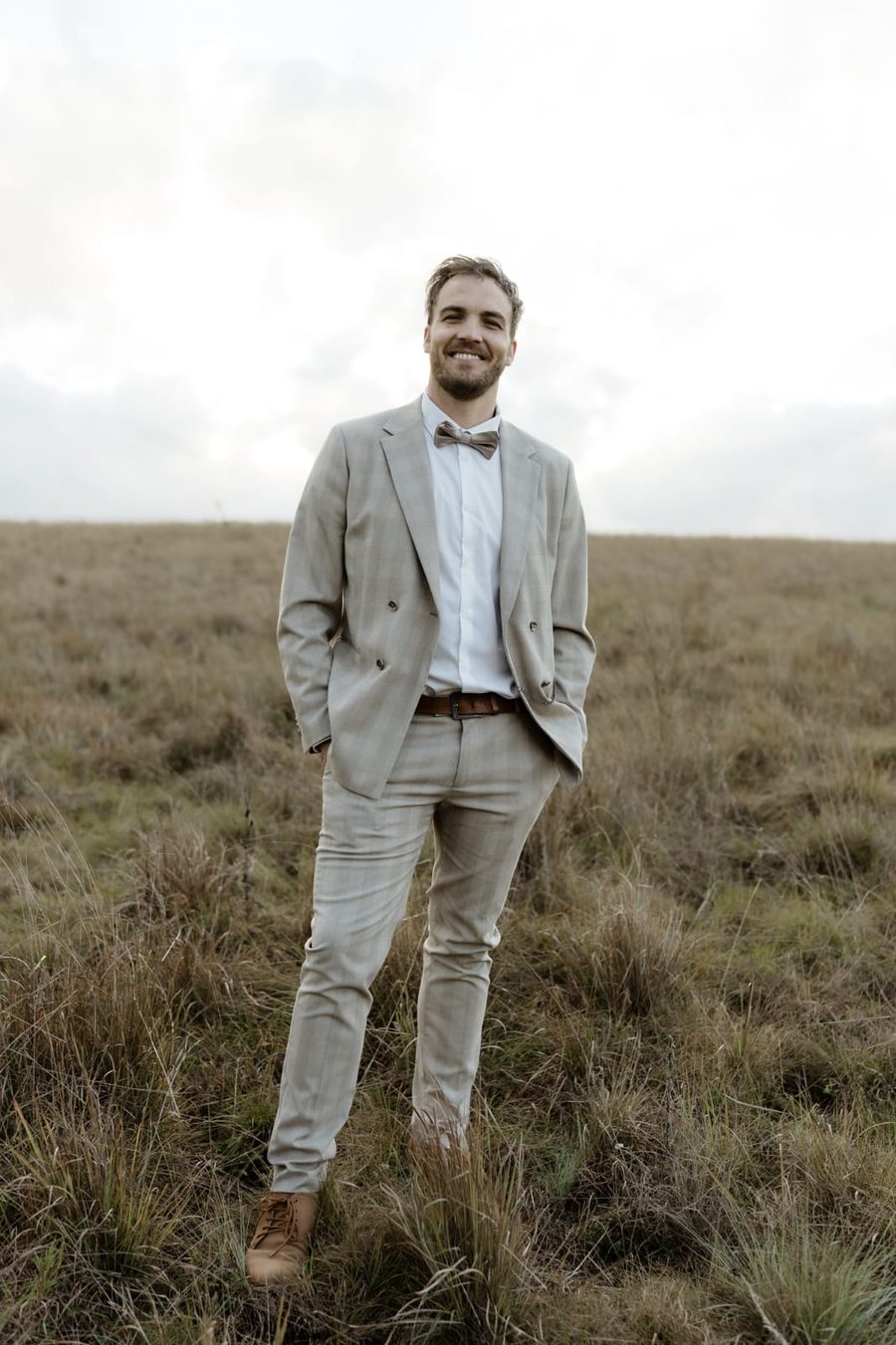 Dr Mitchell J Gow standing in open highveld grassland